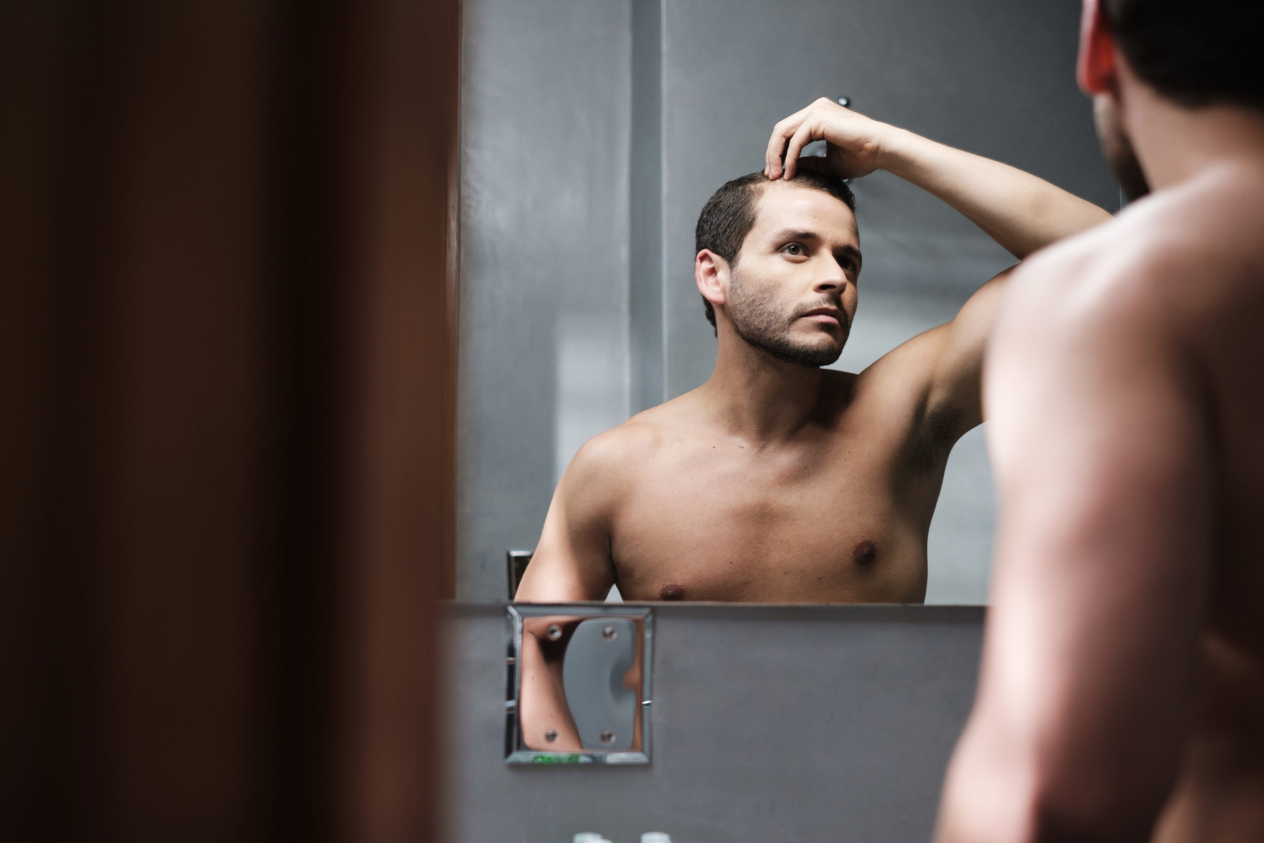 Man checking his hairline in a mirror